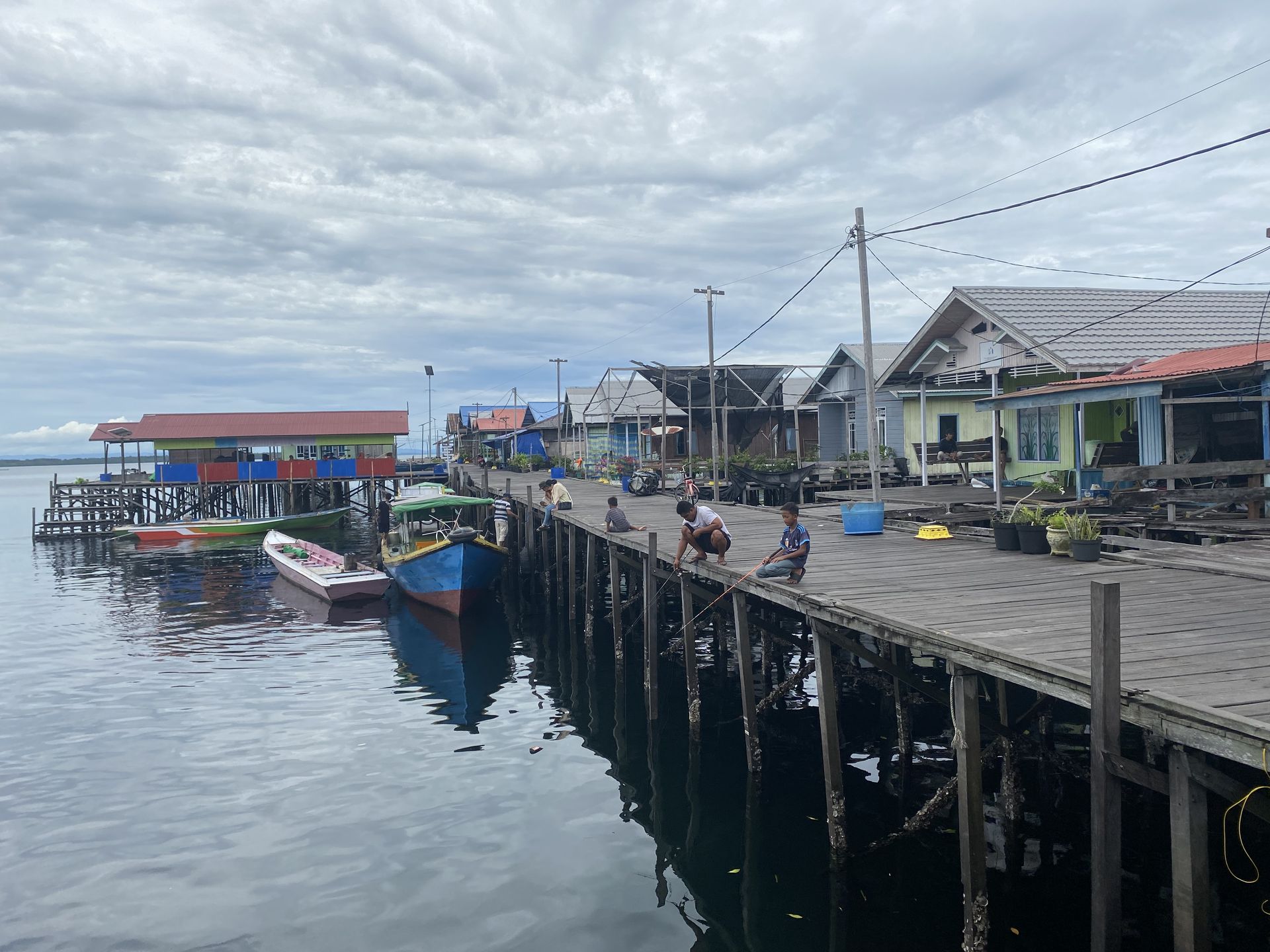 Warga lokal Pulau Miang sedang memancing di perairan jernih, menampilkan kehidupan tradisional dan suasana tenang desa nelayan.